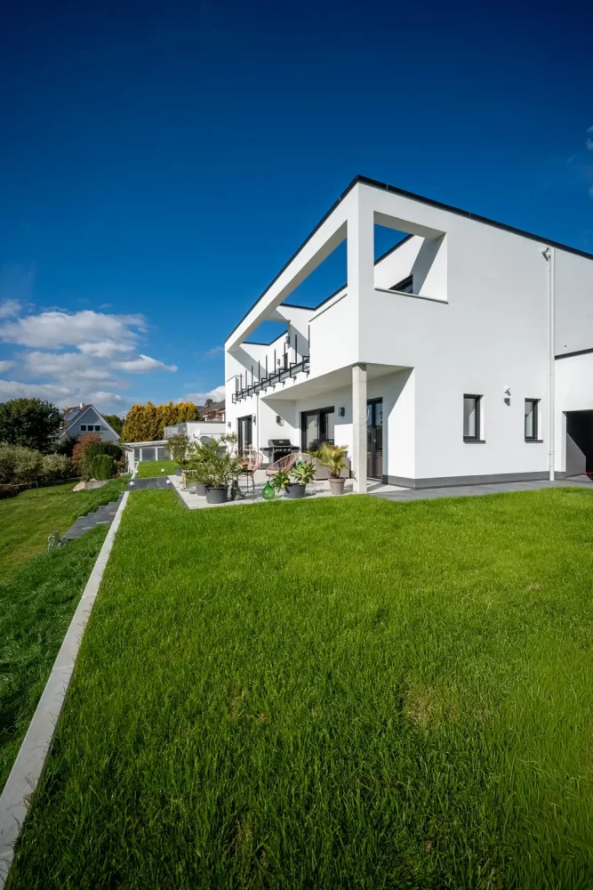 Massivhaus bauen: Modernes Haus im Bauhausstil mit offener Dachterrasse auf erhöhtem großen Rasengrundstück