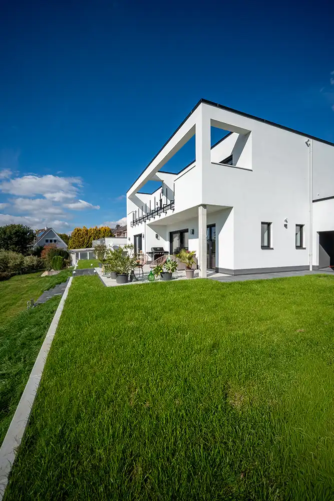 Startseite 3 Massivhaus bauen: Modernes Haus im Bauhausstil mit offener Dachterrasse auf erhöhtem großen Rasengrundstück