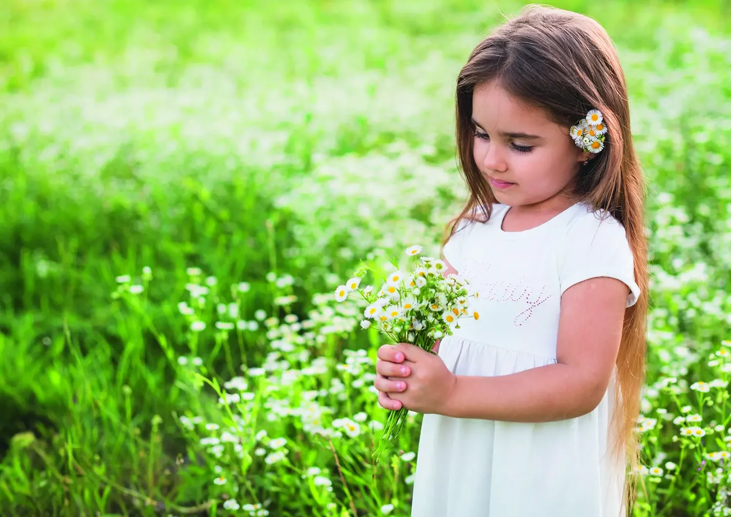 Ökologisch und wohngesund 1 Mädchen in weißem Kleid steht auf einer grünen Wiese und pflückt Blumen zu einem Strauß