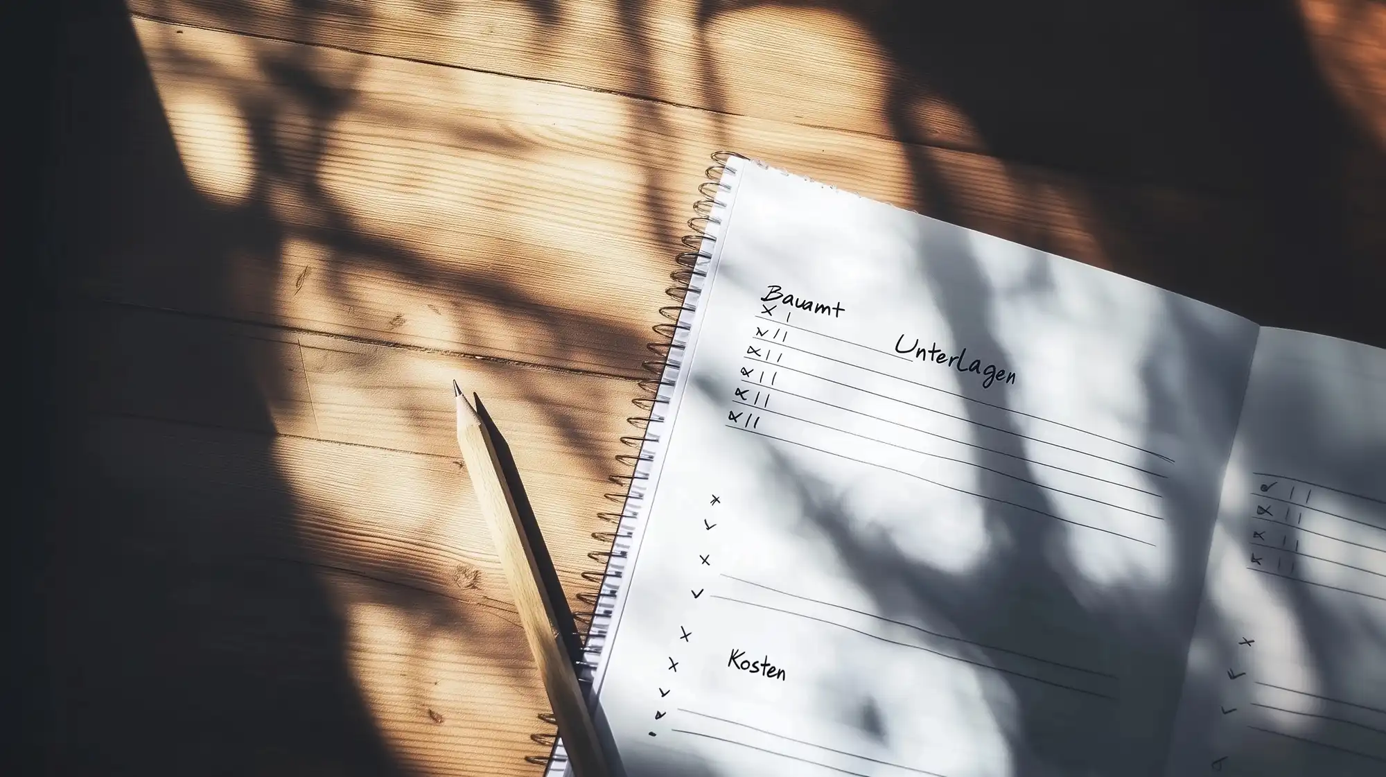 Bauantrag stellen: Ein Notizbuch mit handschriftlichen Listen und dem Stichwort „Unterlagen“ liegt auf einem Holztisch – es scheint zur Vorbereitung, um einen Bauantrag zu stellen.