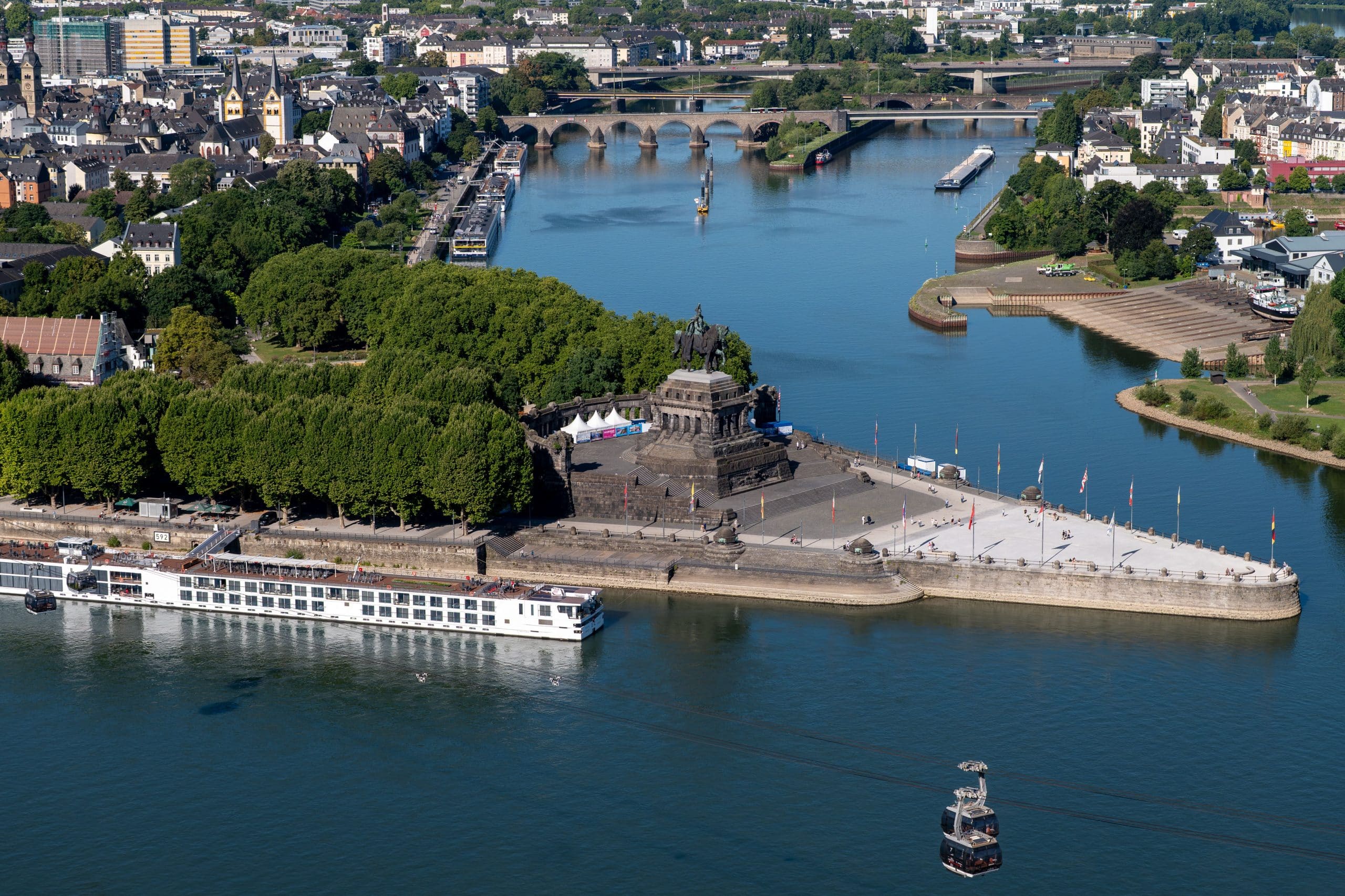 Bauträger Koblenz: Flusslandschaft mit Denkmal und Seilbahn.