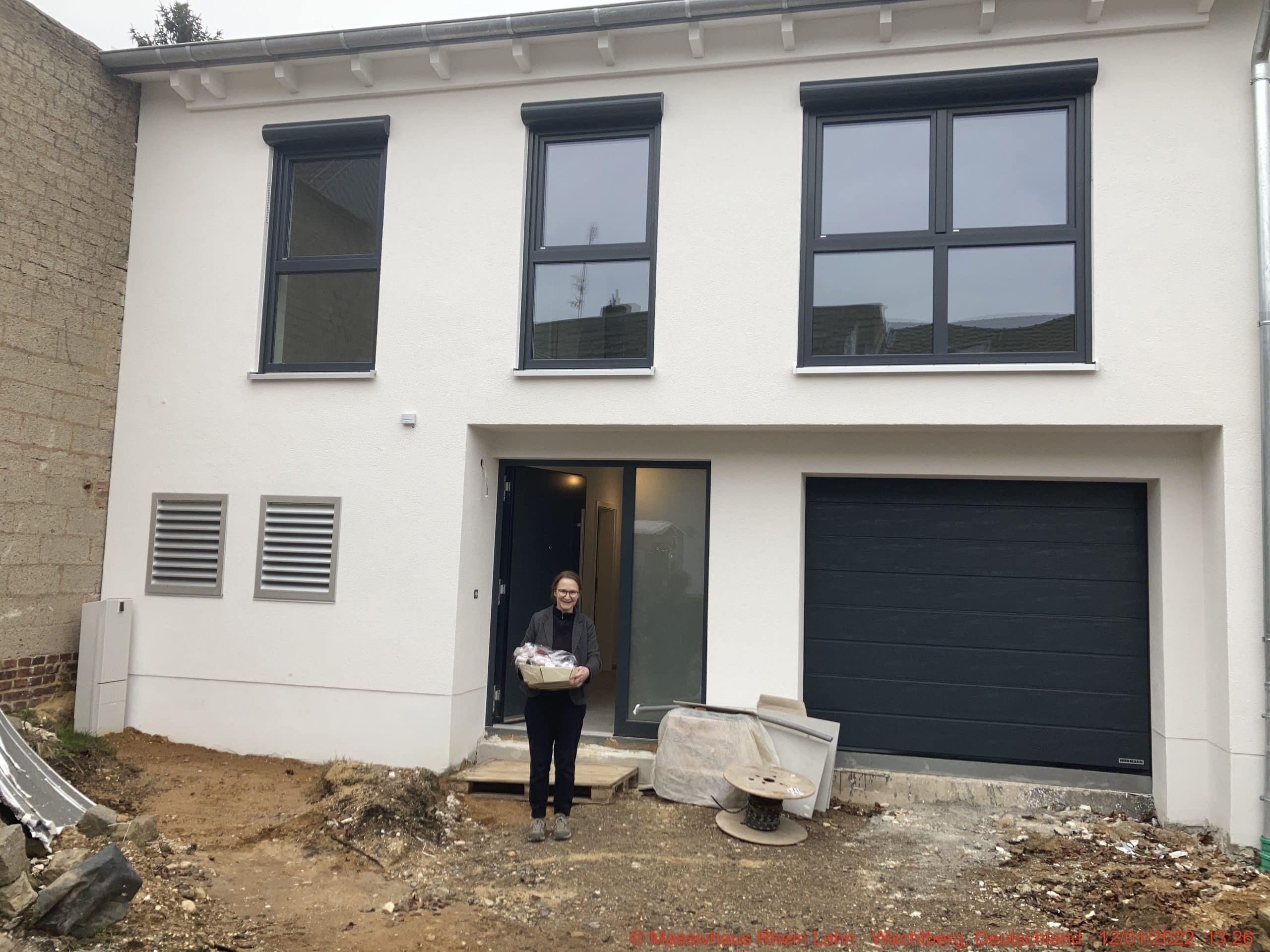 Schwieriges Grundstück bebauen 10 Frau vor neuem modernen Haus.