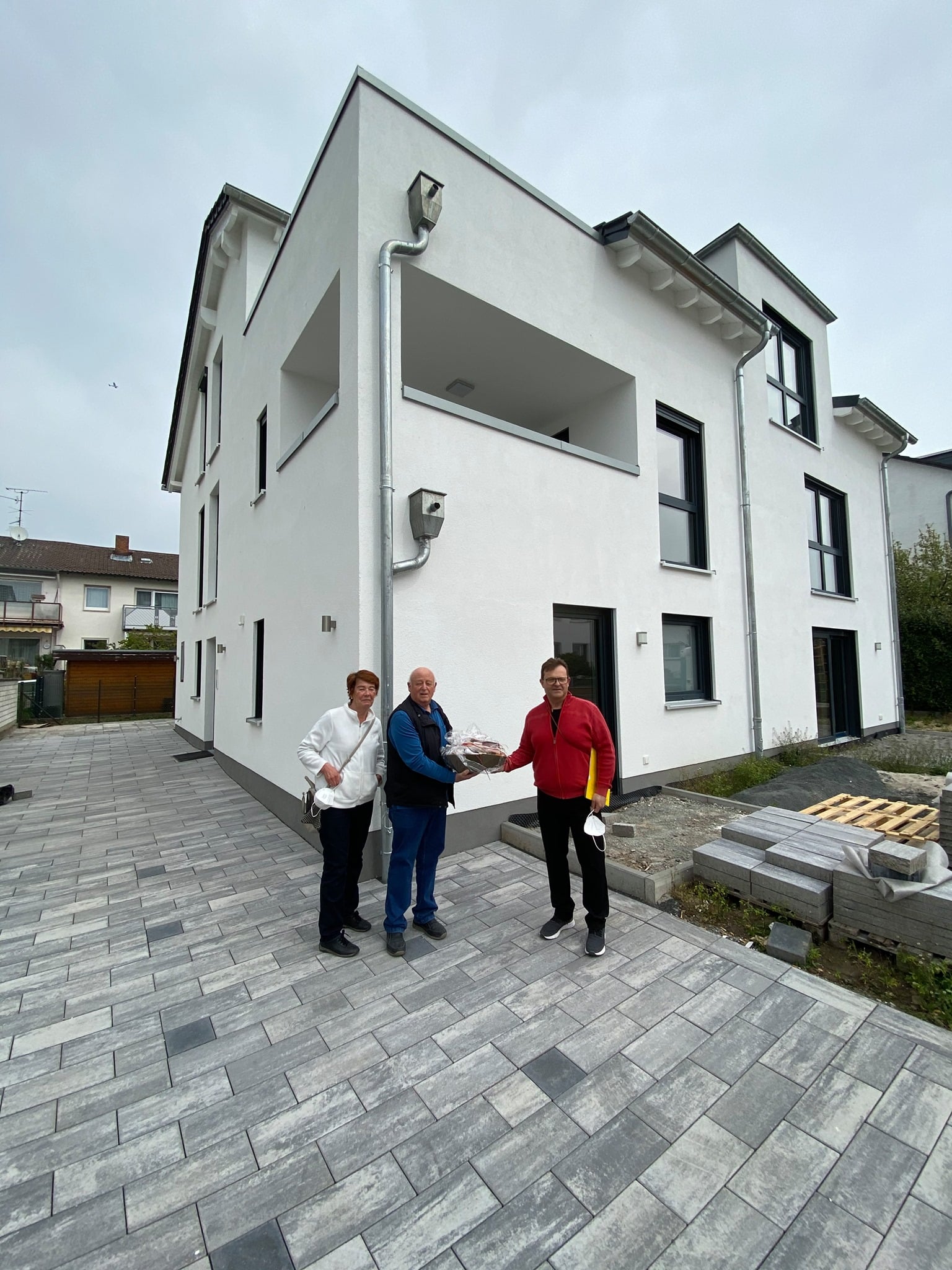 Schwieriges Grundstück bebauen 1 Drei Personen vor modernem Haus.