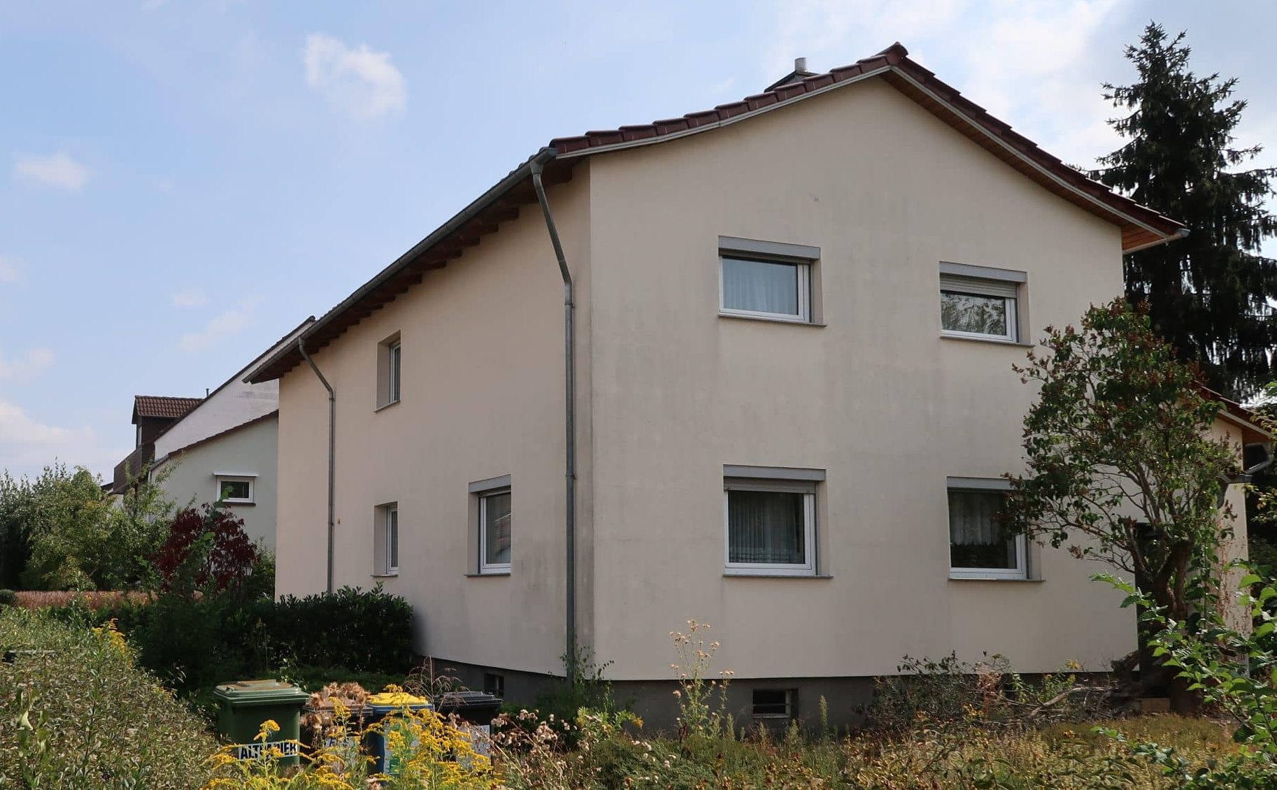 Schwieriges Grundstück bebauen 7 Helles Haus mit Garten und Mülltonnen.
